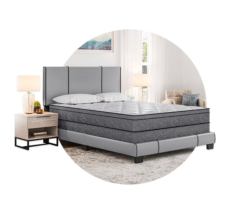 A mattress and upholstered bed in a softly lit bedroom